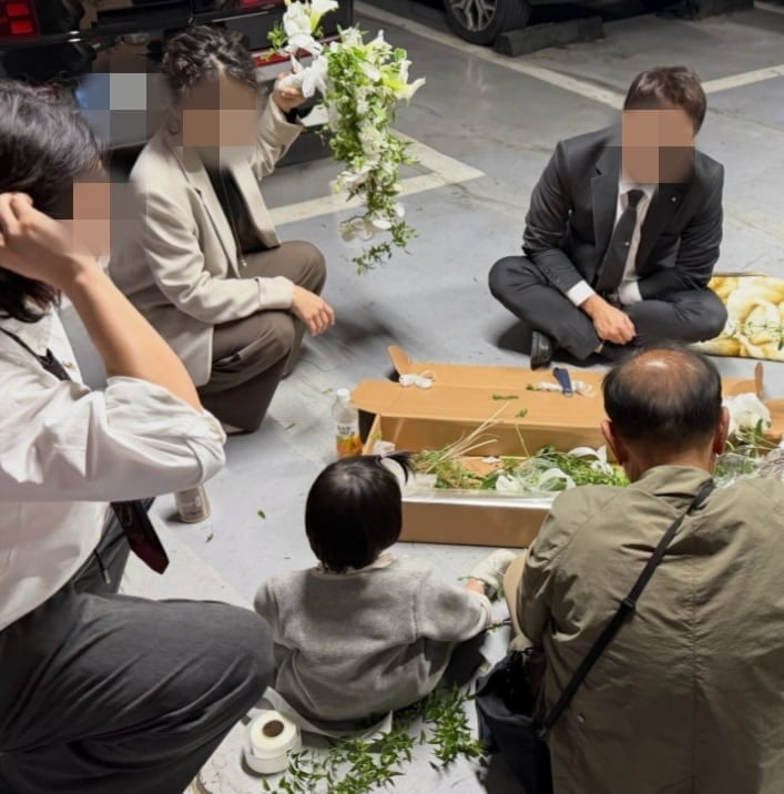 A씨의 아버지가 결혼식장 주자창에서 부케를 만드는 모습을 가족들이 지켜보고 있다. / 사진=스레드 캡처