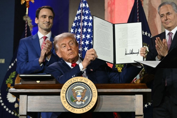 지난해 7월,도널드 트럼프 미국 대통령이 자신이 서명한 'AI 액션 플랜' 행정명령서를 들어 보이고 있다,/AFP