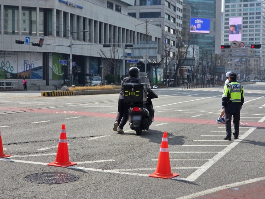 한 배달원이 교통통제 구역에서 오토바이에서 내려 끌고 이동하고 있다./사진=이정우 기자