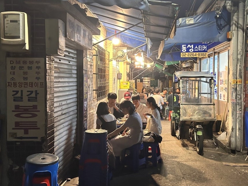 22일 서울 인현동 인현시장 골목에서 시민들이 노포 앞 간이 테이블에 앉아 술잔을 기울이고 있다.