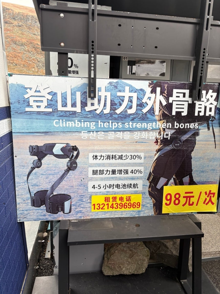 지난 25일 중국 지린성 백두산 천지로 향하는 계단 아래 외골격 웨어러블 로봇 대여소에서 관광객들이 제품을 착용하고 있다. 한 번 대여료는 98위안으로 허리와 양쪽 허벅지에 장치를 착용하면 센서가 보행을 감지해 오르
