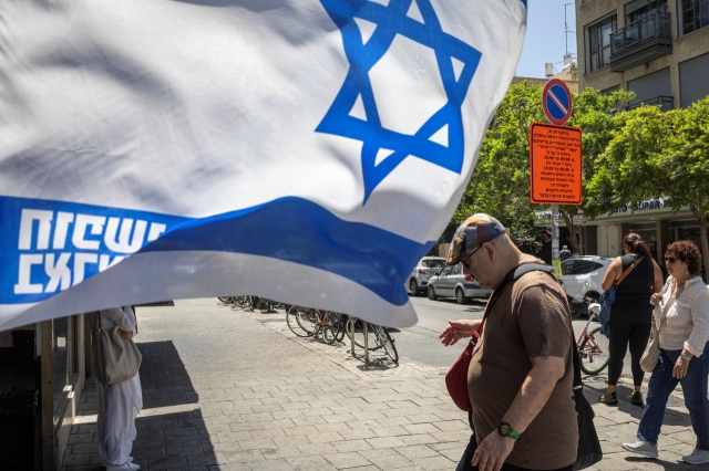 A citizen in Tel Aviv, Israel passes by the Israeli flag on the 16th (local time). [Reuters]