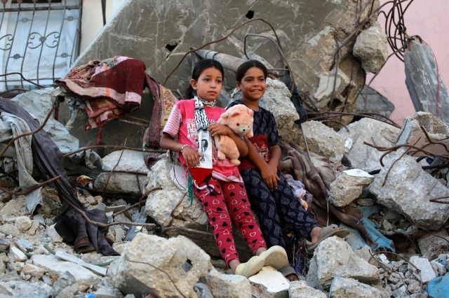 On the 16th (local time), Palestinian girls lean against the rubble in Gaza where large-scale bombings have disappeared. [AFP]