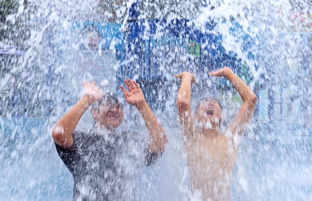 On the 25th afternoon, most areas of the country are under a heat wave advisory, students at a water park in Bukgu Citizen's Forest in Gwangju are cooling off in the heat under a spray of water. [Yonhap]