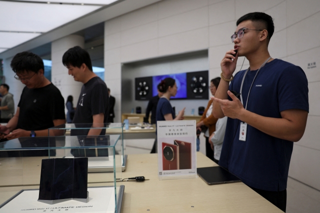 People looking at smartphones in a Huawei flagship store. [Reuters]