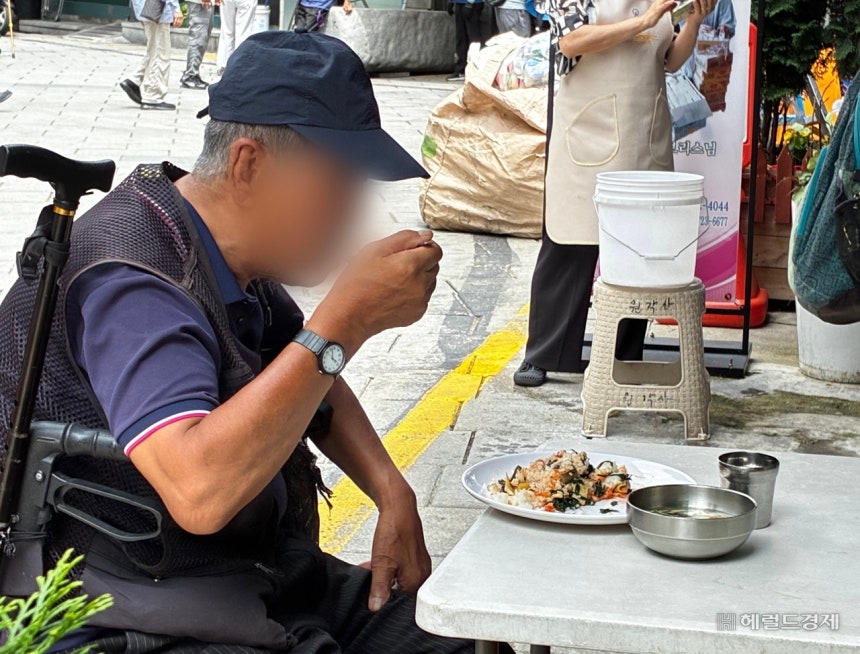 13일 오후 12시께 서울 종로구 원각사 무료급식소에서 점심 배식을 받은 한 노인이 급식소 앞 야외 테이블에서 식사를 하는 모습.김서현 수습기자