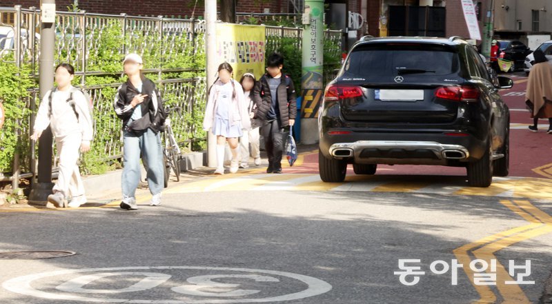 지난달 23일 서울 양천구의 한 초등학교 근처 스쿨존(어린이보호구역)에서 아이들이 인도와 차도의 구분이 없는 도로를 걸어 등교하고 있다.아이들 옆을 차가 지나가고 있다.장승윤 기자 