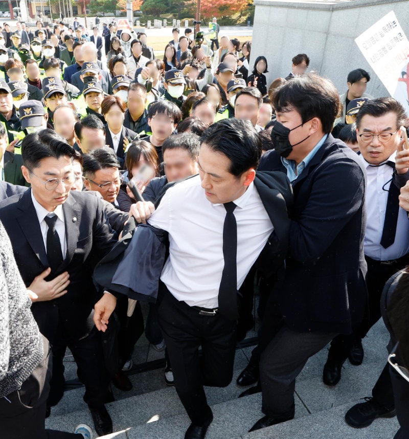 6일 광주를 방문한 국민의힘 장동혁 대표가 국립5·18민주묘지를 참배하기 위해 이동하고 있다. 이날 장 대표는 시위대의 저지를 뚫고 가까스로 추모탑에 도착했지만, 시민단체의 반발이