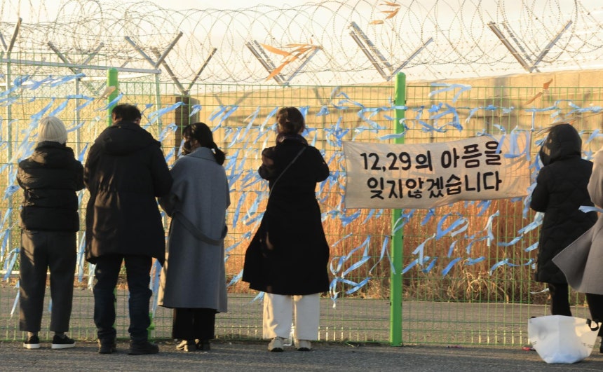 제주항공 여객기 참사 1주기를 앞둔 21일 전남 무안국제공항 사고 현장 인근 공항 철조망에서 희생자 유가족들과 추모객들이 파란린본을 매달고 있다.무안=박영철 기자 