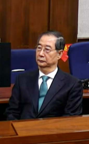 한덕수 전 국무총리가 21일 서울중앙지법에서 열린 내란 우두머리 방조와 내란 중요임무종사 혐의에 대한 1심 선고 재판에 참석해 재판장의 발언을 듣고 있다.서울중앙지법 재판 중계 화면 캡처