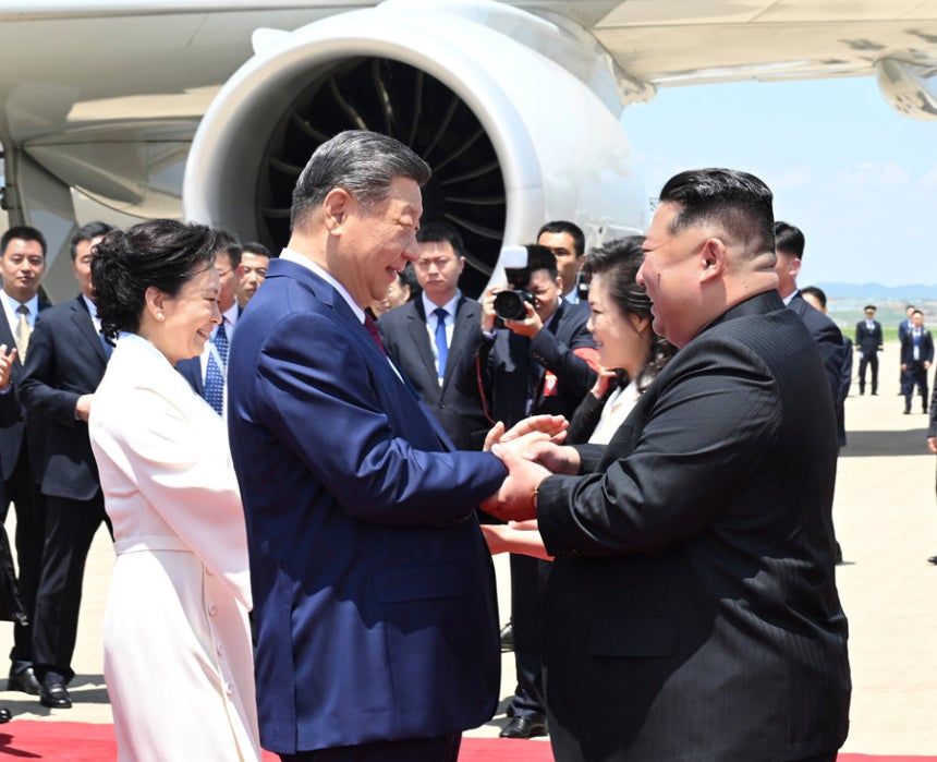 8일 북한 평양 순안공항에 도착한 시진핑 중국 국가주석(앞줄 왼쪽)과 김정은 북한 국무위원장(앞줄 오른쪽)이 환하게 웃으며 손을 맞잡고 있다.시 주석의 부인 펑리위안 여사(뒷줄 왼쪽)와 김 위원장의 부인 리설주(뒷
