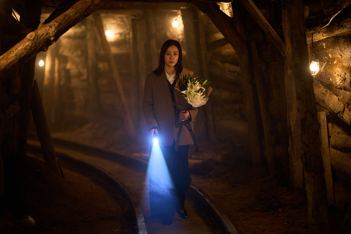 映画『失楽園』で花束とライトを手に暗い坑道を歩くキム・ヒョンジュ