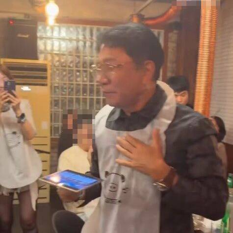 飲食店でエプロン姿のイ・スマン氏が客に声をかける様子