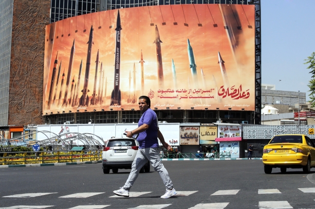 4월 19일 이란 테헤란에서 한 이란 남성이 미사일 그림위에 페르시아어로 '이스라엘은 거미집보다 약하다'는 문구가 적힌 반 이스라엘 광고판 앞을 지나가고 있다. EPA 연합뉴스