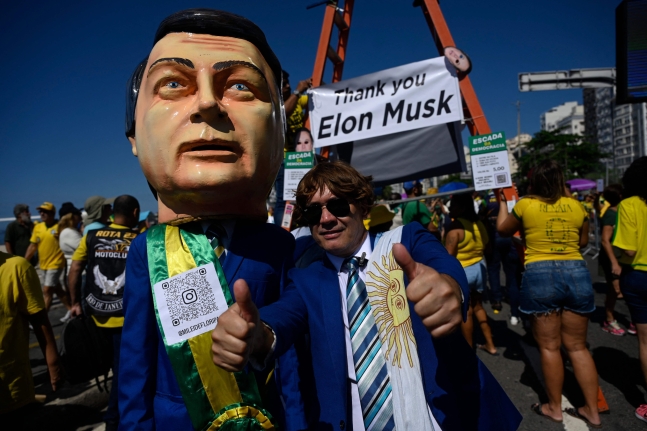 21일 브라질 리우데자네이루에서 열린 집회에 참석한 보우소나르 전 대통령의 지지자가 일론 머스크를 본따 만든 인형과 함께 '고마워요, 머스크' 라고 적힌 팻말을 들고 있다. /AFP 연합뉴스