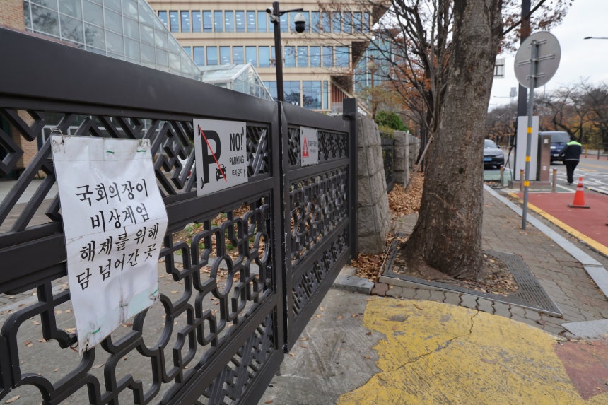 26일 서울 여의도 국회 외곽 철제 문에 ‘우원식 국회의장이 비상계엄 해제를 위해 담 넘어간 곳’이란 문구의 표지판이 걸려있다. 국회는 계엄 1년을 맞아 각종 행사 등에 최소 4억3100여 만원의 예산을 쓸 것으로