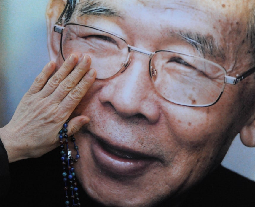 지난 2009년 김수환 추기경 선종 후 명동성당 앞에 전시된 그의 사진을 한 신자가 어루만지고 있다.김 추기경은 생전에 '옹기'라는 아호를 썼다./조선일보DB