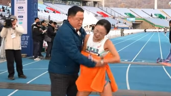 지난 11월 23일 열린 2025 인천국제마라톤대회에서 결승선을 통과한 이수민 선수가 부축하기 위해 감싸안는 김완기 감독의 손을 뿌리치고 있다./KBS스포츠 유튜브
