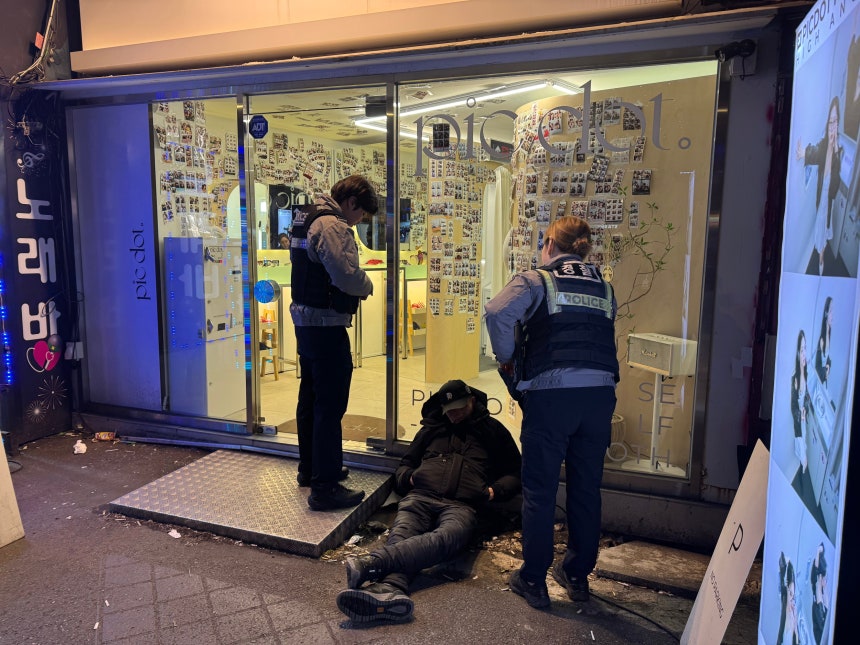 지난달 30일 밤 서울 영등포구의 한 무인 사진관 앞에 중년 남성이 술에 취해 쓰러져 있다.경찰이 출동해 남성을 살피고 있다./윤성은 기자