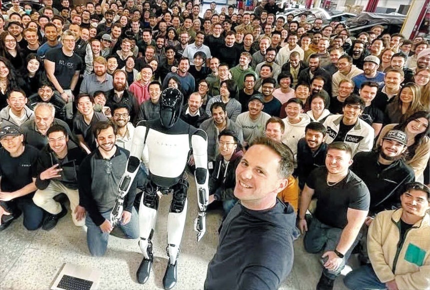  X옵티머스 개발진과 기념 촬영 자신이 개발을 주도한 휴머노이드 로봇 옵티머스를 앞에 두고 동료 직원들과 기념 촬영을 하고 있는 밀란 코박 전 부사장(맨 앞 서 있는 이).현대차그룹은 16일 그를 자문역으로 영입