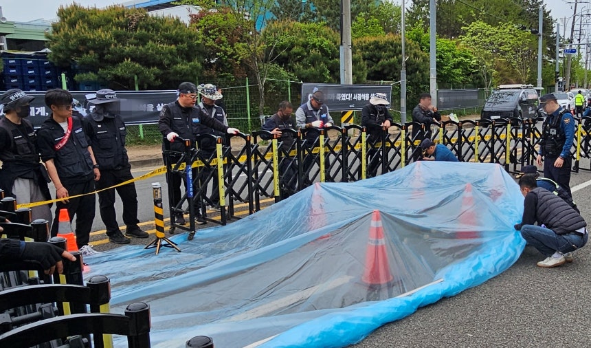 22일 경남 진주시 정촌면 CU 진주물류센터 앞 민주노총 화물연대 조합원이 사망한 사고 현장 보존을 위해 조합원과 경찰이 방수포 작업을 하고 있다./뉴스1