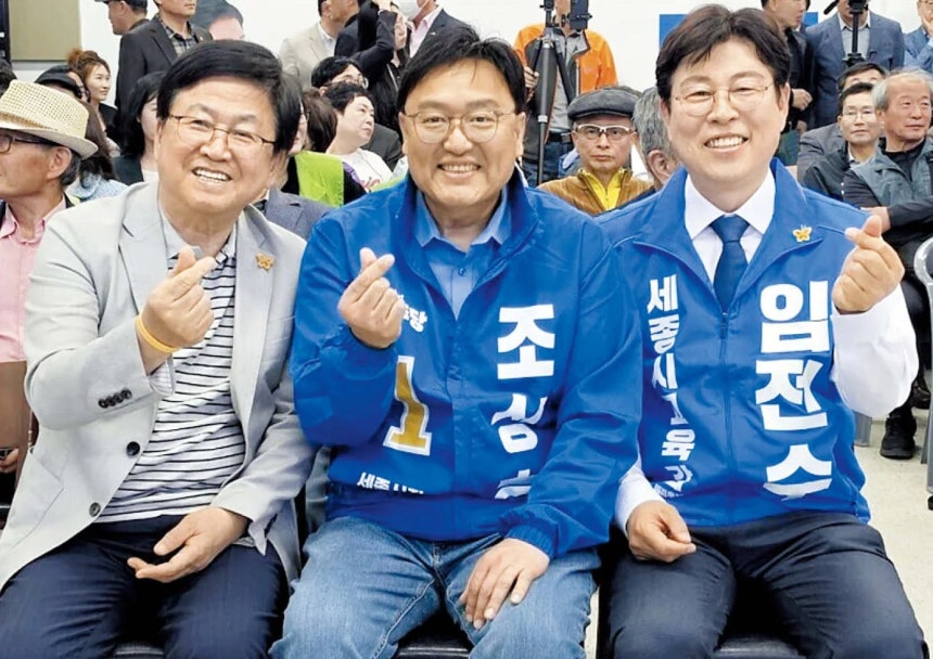 최교진 교육부 장관(왼쪽)이 4월 25일 세종시 나성동에서 열린 임전수 세종시교육감 예비후보(오른쪽) 선거사무소 개소식에 참석해 손가락으로 하트 모양을 만들어 보이고 있다.가운데는 조상호 더불어민주당 세종시장 예비