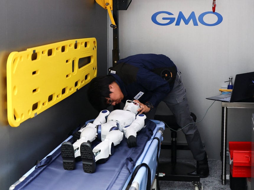 일본 도쿄에서 최근 공개된 휴머노이드 전용 정비 차량‘GMO 휴머노이드 앰뷸런스’에서 엔지니어가 구급용 들것에 누워있는 휴머노이드 로봇의 상태를 살펴보고 있다./로이터 연합뉴스
