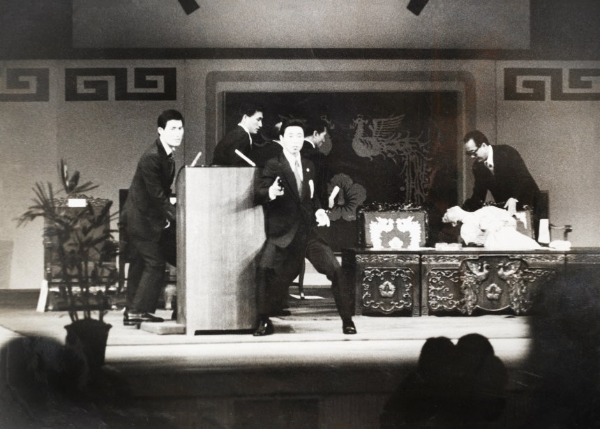1974년 8월 15일 서울 장충동 국립극장 광복절 기념식 중 문세광이 총탄을 발사한 직후의 상황.박정희 대통령은 연설대 뒤로 몸을 피한 상태에서 경호관들이 그곳을 둘러싸고 있고,오른쪽엔 문세광의 총탄을 맞고 쓰