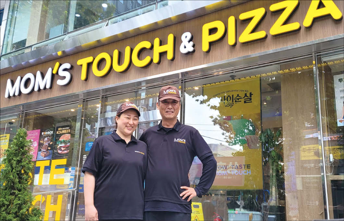 강재구 맘스터치 3개 점주(오른쪽)가 아내와 함께 맘스터치 대치사거리점 앞에서 포즈를 취하고 있다.(맘스터치 제공)