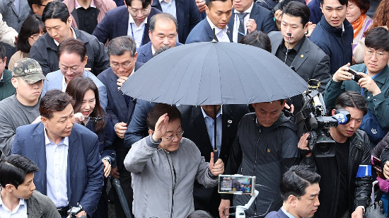 이재명 더불어민주당 대선 후보가 지난 3일 강원도 속초시 중앙재래시장에서 비가 그쳤음에도 우산을 쓴 채로 두터운 경호막에 둘러싸여 도민들을 향해 인사하고 있다.(사진=연합뉴스)
