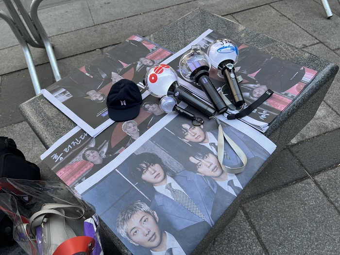  BTS의 팬들은 여러 언론사가 배부한 신문과 BTS 공식 응원봉인‘아미봉’을 함께 놓고‘인증샷’을 찍는다.(이채원 기자)