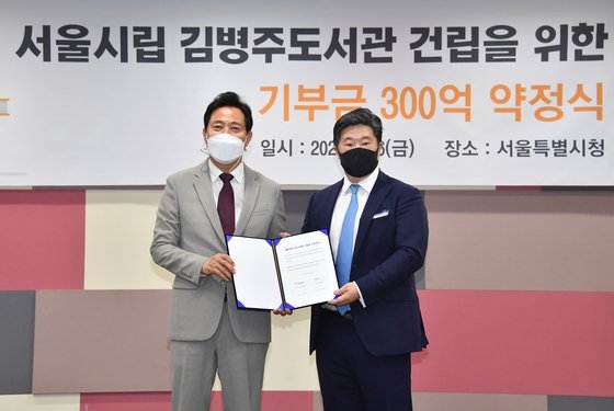 MBK파트너스 김병주 회장(오른쪽)이 지난 6일 서울시청에서 열린 서울시립도서관 건립 기부금 전달식에서 오세훈 시장과 기념촬영을 하고 있다. 사진 서울시