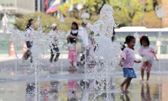 서울 낮 최고기온이 28도를 기록한 13일 서울 종로구 광화문광장 분수대에서 어린이들이 놀고 있다. 뉴스1