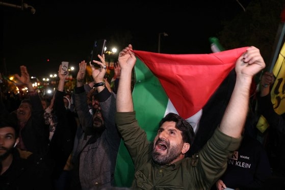 이란이 이스라엘에 무인 공격기(드론)와 미사일 공격을 가한 후 14일(현지시간) 이란 테헤란 주재 영국 대사관 앞에 모인 시위대들이 이란 국기를 흔들고 있다. 로이터=연합뉴스