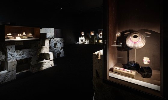 ‘까르띠에, 시간의 결정’의 전시장 모습. 오랜 시간을 머금은 일본 오야석이 채석장처럼 거친 느낌을 연출해 내고 있다. 불상 제작 장인이 1000년 이상 된 나무를 깎아 만든 토르소에 걸린 까르띠에의 네크리스가 빛을