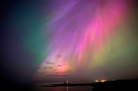 10일 영국 북동부 해안 휘틀리 베이의 세인트 매리 등대에서 오로라가 수평선 위로 빛나고 있다. AP=연합뉴스