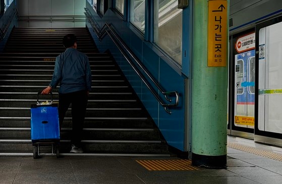 지하철 이동상인 김모(76)씨가 지난 5월 27일 파란 통이 달린 카트를 끌고 자신이 방금 내린 열차를 쳐다보고 있다. 김홍준 기자
