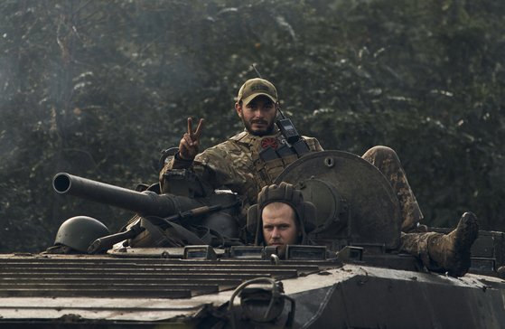 러시아가 점령했던 우크라이나 북동부 하르키우 인근의 전략적 요충지인 이지움을 수복한 우크라이나 군인이 지난 2022년 9월 13일 BMP-2 보병전투차를 타고 승리의 V자를 보이고 있다. AP=연합뉴스
