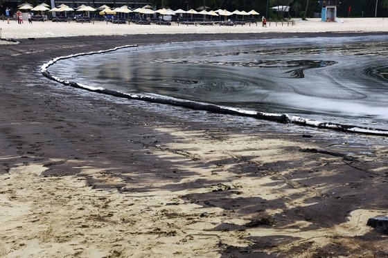 15일(현지시간) 파도에 밀려온 기름띠로 검게 물든 싱가포르 센토사섬 탄종 해변. 로이터=연합뉴스