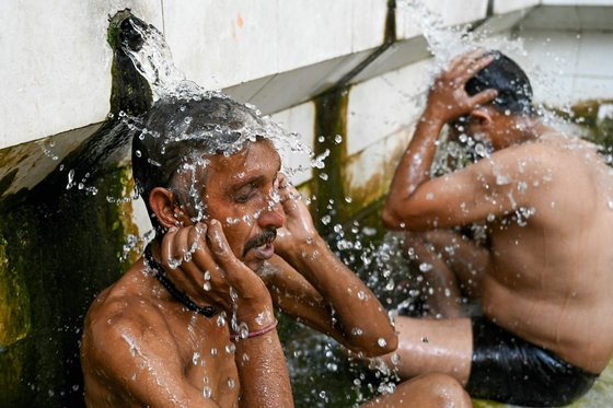 14일(현지시간) 인도 암리차드 지역의 주민들이 45도 폭염 속 공중 욕탕에서 물을 끼얹으며 더위를 식히는 모습. AFP=연합뉴스