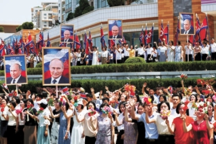 푸틴 러시아 대통령의 사진과 꽃을 들고 거리에서 환영하는 평양 시민들. 19일 모습이다. AP=연합뉴스ㄴ
