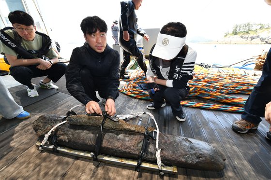 26일 전북 군산시 선유도 해역에서 진행된 국립해양유산연구소 수중 발굴 조사에서 발견된 선박 일부로 추정되는 목재 조각을 관계자들이 살펴보고 있다. 사진 국가유산청