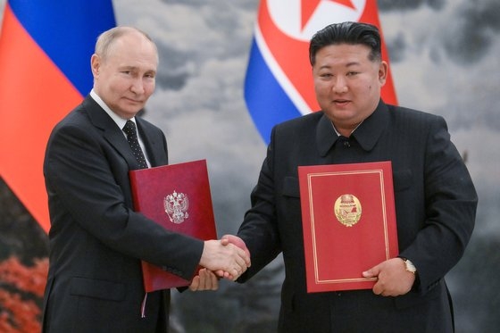 푸틴 러시아 대통령(왼쪽)과 김정은 북한 국무위원장이 지난달 19일 평양 에서 정상회담 뒤 서명한 조약을 들어 보이고 있다. 타스=연합뉴스