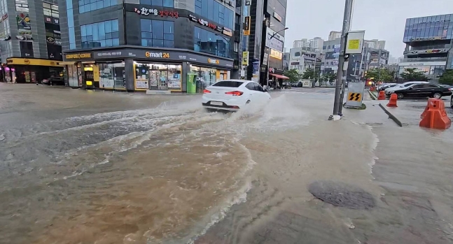 지난 18일 충남 서산에 내린 집중호우로 침수된 도로를 차량이 달리고 있다. 연합뉴스