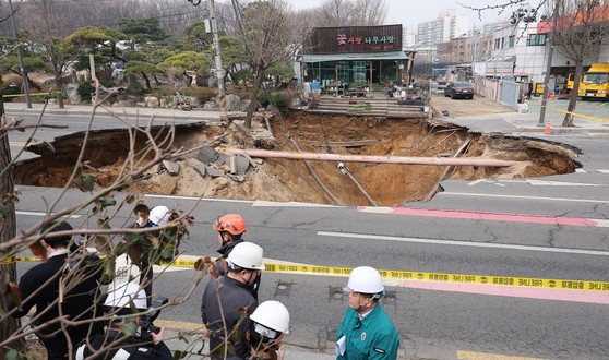 지난달 25일 서울 강동구 대명초등학교 인근 사거리에서 싱크홀(땅 꺼짐) 사고 발생으로 교통이 통제되고 있다. 전날 오후 6시 29분쯤 명일동의 한 사거리에서 지름 20ｍ, 깊이 20ｍ가량의 대형 싱크홀이 발생했다.