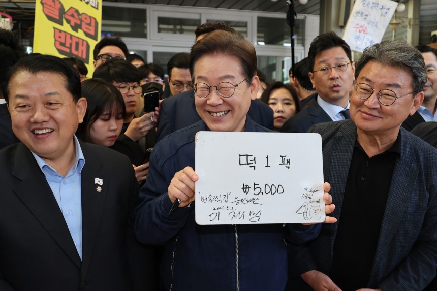 이재명 더불어민주당 대선 후보가 ‘골목골목 경청투어’ 접경지역 방문 이틀째인 2일 강원도 철원군 동송전통시장에서 한 떡집에 들러 가격판에 사인을 해준 뒤 활짝 웃고 있다. 연합뉴스