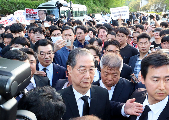 2일 오후 광주 북구 국립5ㆍ18민주묘지를 찾은 한덕수 전 총리가 광주비상행동 등 시민사회단체 관계자들에게 가로막히자 발길을 돌리고 있다. 연합뉴스