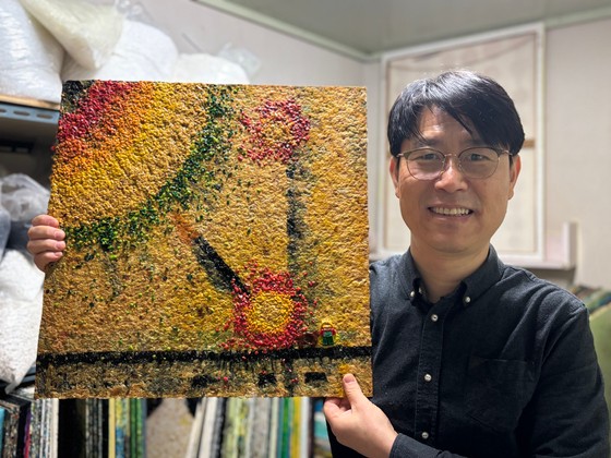 박준성 사단법인 트루 사무총장이 플라스틱 판자 '널'을 들고 서 있다.트루는 기부받은 폐장난감에서 플라스틱을 분해해 가루를 낸 후,고온으로 압착해 플라스틱 판자 널을 만들어낸다.널은 가구,인테리어 소재 등으로