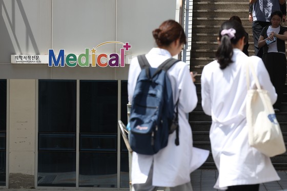 전국 의대 유급·제적 명단 정부 제출 마감일인 7일 오전 서울 시내의 한 의과대학에서 의사 가운을 입은 학생들이 이동하고 있다. [연합뉴스]