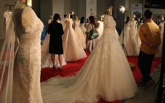 2020년 부산에서 열린 제46회 대한민국웨딩산업박람회'에서 업체 관계자들이 웨딩드레스 제품을 살펴보고 있다.송봉근 기자